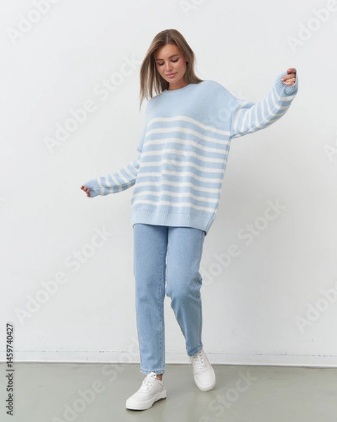 Fototapeta Stylish model showcases playful fashion in soft blue hues during studio shoot