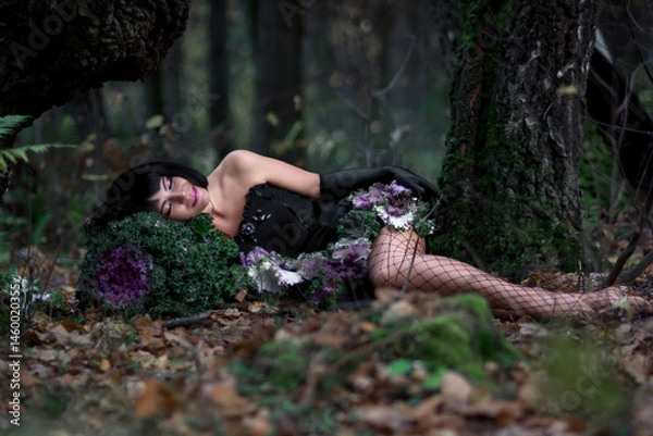Fototapeta Slender brunette beauty in the image of a forest fairy lies on the ground. Decorative cabbage instead of a bouquet. Artistic creative photography.