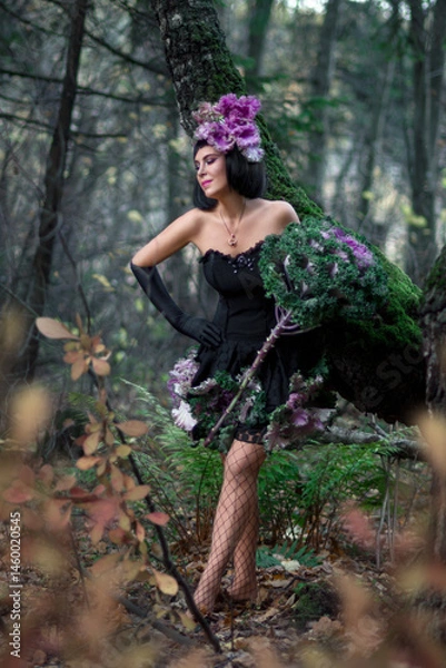 Fototapeta Slender beautiful brunette in the image of a forest fairy in full growth. Decorative cabbage instead of a bouquet. Artistic creative photography.