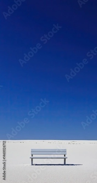 Fototapeta Empty bench on a vast, white expanse beneath a vibrant blue sky