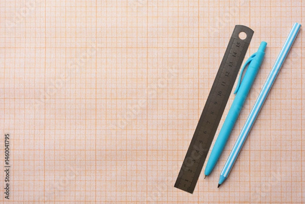 Fototapeta Concept of studying at school and back to school. Pens, pencils and ruler on school squared paper background, copy space