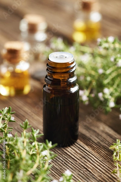 Fototapeta A dark bottle of thyme essential oil on a wooden background