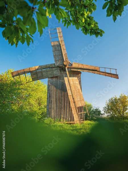Obraz portrait view to wooden mill in Ukraine through green leaves of trees