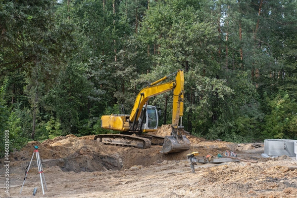 Obraz A yellow excavator is digging in the dirt