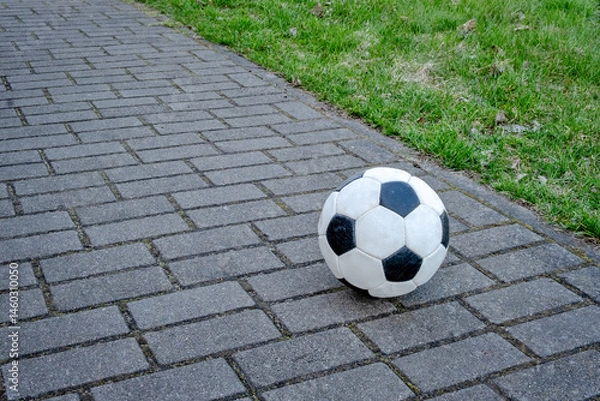 Obraz A white and black soccer ball is laying on a brick walkway