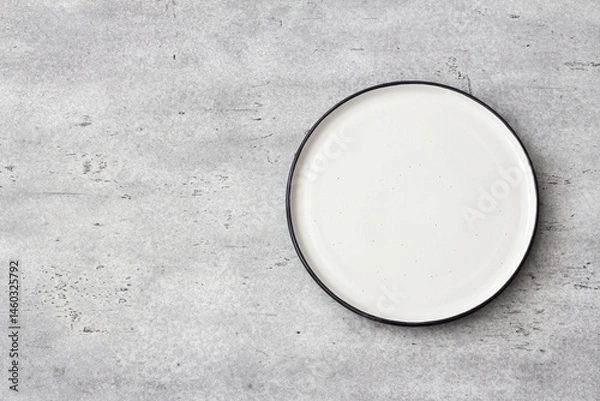 Obraz Empty round white ceramic plate with black rim on concrete gray textured background. Minimalist table setting, top view. Ideal for food mockups and design templates