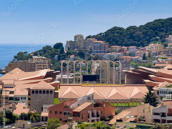 Fototapeta Principality of Monaco, France - July 9, 2024: Place du Palais, Palace Square. Looking over the south rampart shows lots of new buildings, forest and sea. Bows above Sport Stadium Louis II