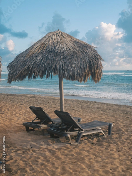 Obraz view of a resting place with long chair on a beach ext to the ocean with a straw umbrella
