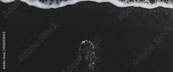 Obraz Foot in dark sand as ocean water washes shore in monochrome beach scene, nature?s power on display