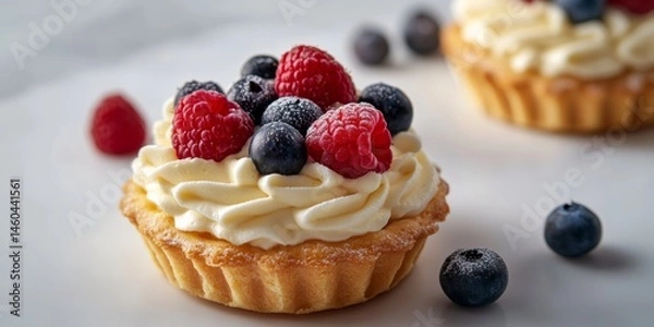 Fototapeta Delicious berry tart topped with creamy frosting and fresh raspberries and blueberries prepared with care at a pastry shop