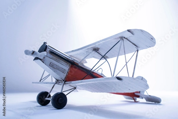 Fototapeta Vintage toy biplane evoking nostalgia and adventure on a white background of light and shadows