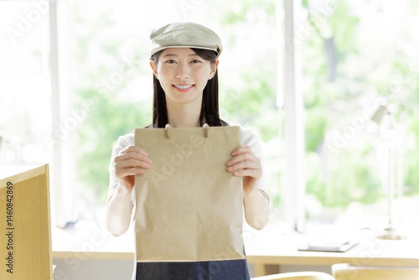 Obraz 注文品をお客に渡すカフェの女性店員
