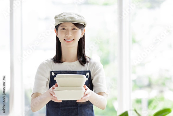 Obraz 注文品をお客に渡すカフェの女性店員
