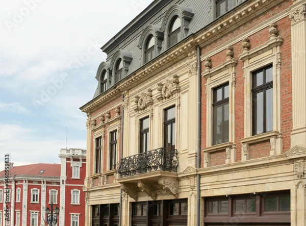 Fototapeta Facade featuring Neo Renaissance pilasters and Neo Baroque stone carvings beneath a slate mansard roof with arched dormer windows and wrought iron balcony on white background