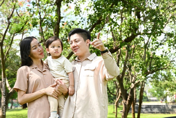 Obraz A family of four is walking in a park, the family appears to be happy and enjoying their time together.