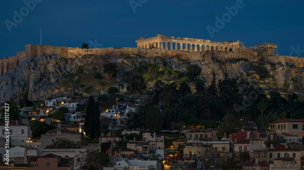 Fototapeta The Parthenon, Athens, overlooking the old town, as the first hint of light enters the sky, whikle the city lights still illuminate the scene