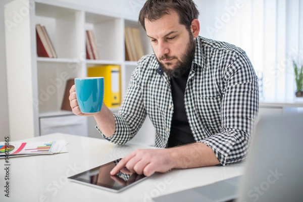 Fototapeta Handsome man working on tablet in office