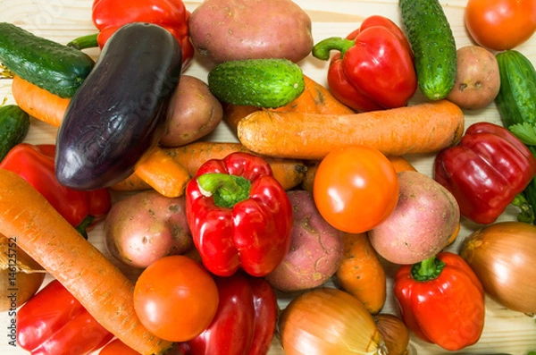 Fototapeta Colorful vegetables on wooden table background. Cooking preparation background. Tomato, pepper, cucumber and over vegetables on the kitchen desk.