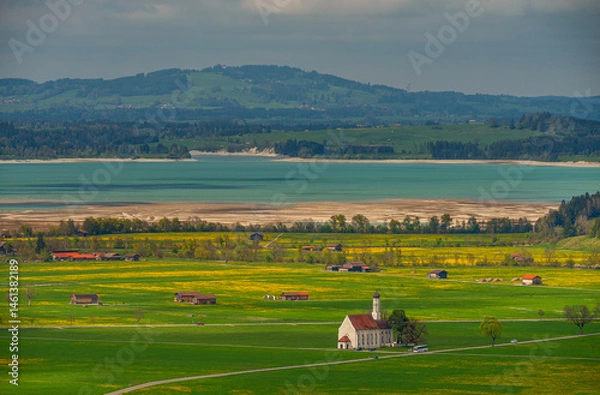 Fototapeta beautiful breathtaking view from above on green meadows and a cute church. In the distance an emerald lake and mountains. bavaria in spring. germany.