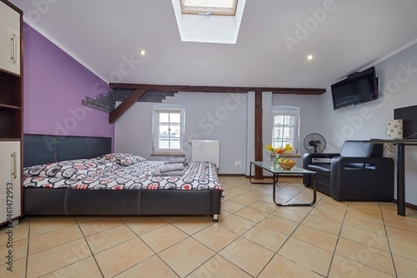 Obraz Kolorowy apartament na poddaszu z dużym łóżkiem i aneksem kuchennym