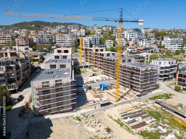 Fototapeta Modern residential buildings under construction with scaffolding and cranes, captured on a clear sunny day