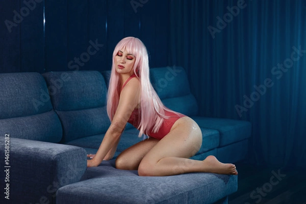 Fototapeta Beautiful blonde posing in erotic pose. Girl in pink bodysuit on sofa.	
