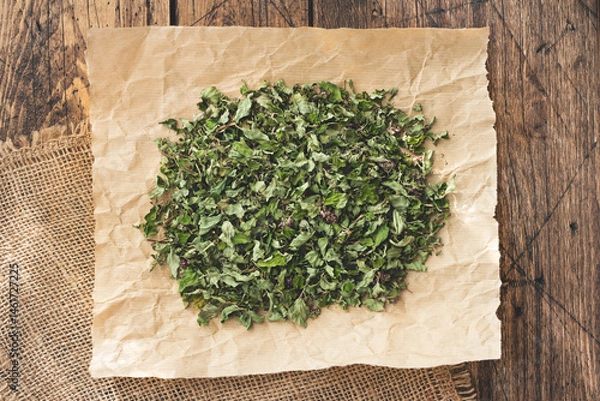 Obraz Close-up of dried oregano on crumpled brown paper on burlap with a rustic wooden table background