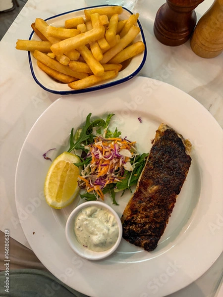 Fototapeta A plate of grilled fish with french fries on the side.