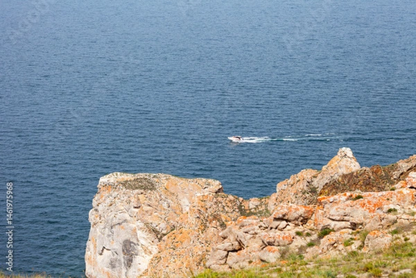 Fototapeta Baikal Lake on summer day. Tourists travel along Small Sea near Olkhon Island and sail past cape Sagan-Khushun or Three Brothers on motor-boat. Summer travel, adventure and outdoor recreation