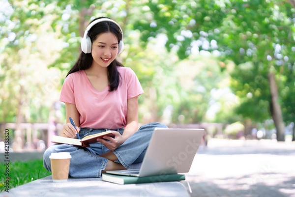 Obraz Asian Young Woman Student Studying Online with Laptop and Headphones in Park Smiling Learning Note Taking Education Lifestyle