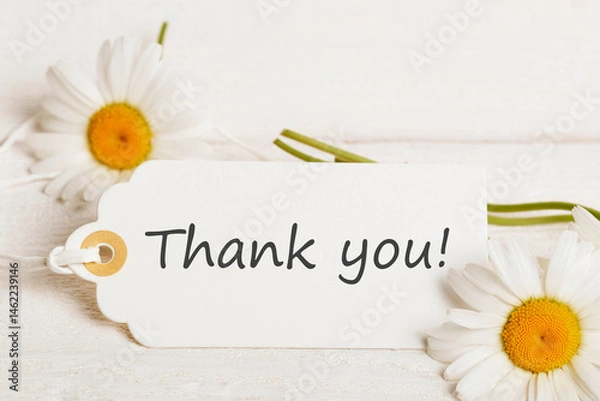 Fototapeta Thank you card with white daisies, rustic wooden background, gift tag with handwritten text, summer greeting design, soft light floral flat lay, natural composition, warm color palette