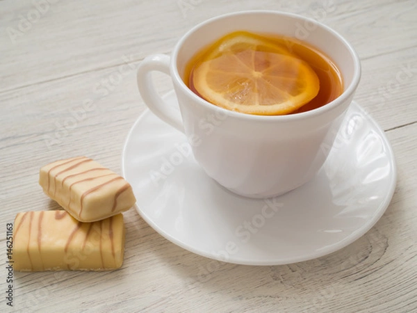 Fototapeta A cup of tea with lemon on a wooden table