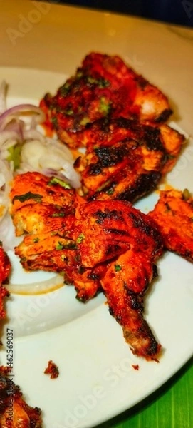 Fototapeta a plate of Tandoori Chicken, a popular Indian dish. The chicken pieces are marinated in a mixture of yogurt and spices, giving them a deep red or orange color, and then cooked in a tandoor 