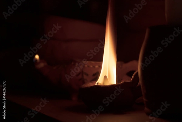Fototapeta A candle is lit in a small holder