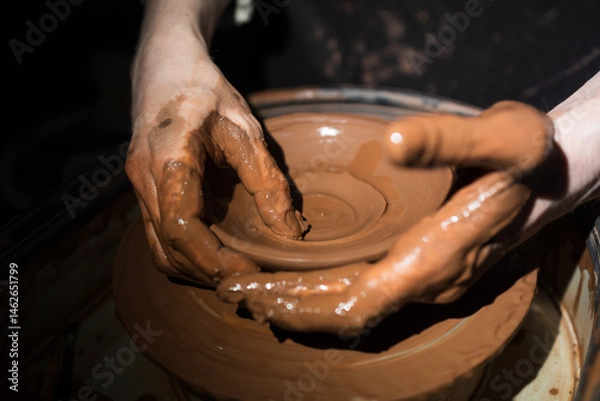 Fototapeta A person is making a pottery piece with their hands