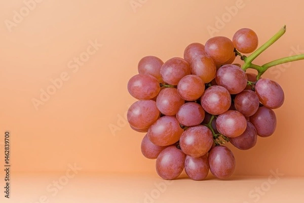 Fototapeta Bunch of fresh red grapes on a soft peach background showing natural colors and textures in a simple arrangement