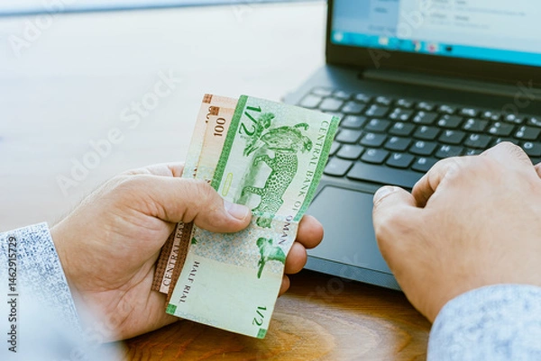 Fototapeta Close up of a man's hand counting money Omani money