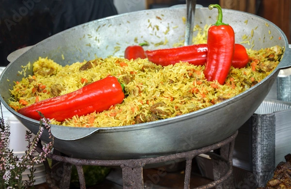 Fototapeta Vibrant pilaf served in a large pan, featuring red peppers and vegetables, perfect for showcasing traditional cooking or fresh ingredients in catering or culinary photography