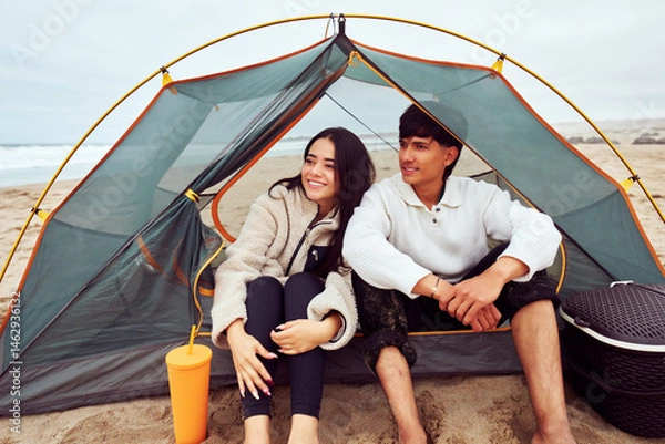 Fototapeta Happy couple relaxing inside tent on beach during camping trip