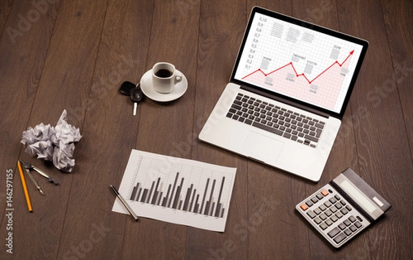 Fototapeta Computer desk with laptop and red arrow chart in screen