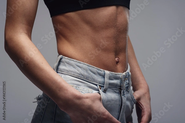 Fototapeta Close-up of a woman's perfect body with abs demonstrating weight loss, slimming.