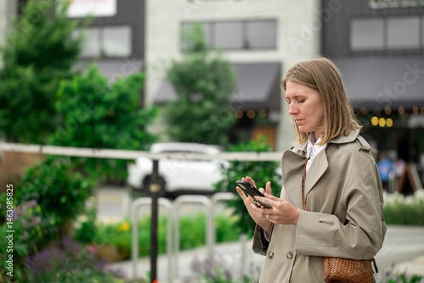 Obraz Woman using smartphone outdoors in urban setting. Businesswoman