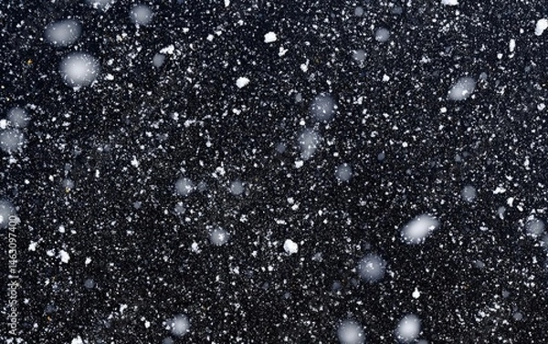 Fototapeta Light snowfall on dark surface. Tiny white flakes scattered across a dark gray backdrop, creating a wintery scene