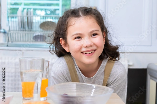 Fototapeta Smiling mother pouring orange juice into a glass for cheerful daughter, capturing family bonding and care, woman and child sharing a happy moment, happiness and warmth in kitchen atmosphere