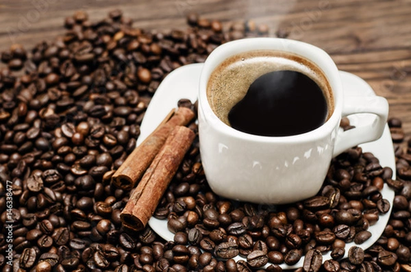 Fototapeta Coffee cup with beans and cinamon on a wooden table