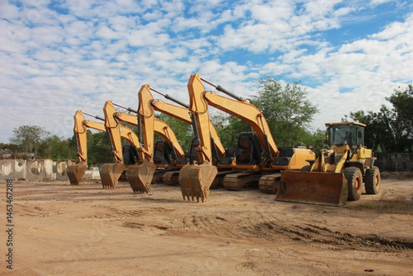 Fototapeta Lots of excavators parked on construction area of industrial building in construction site under the blue sky background.Earthmoving construction equipment
