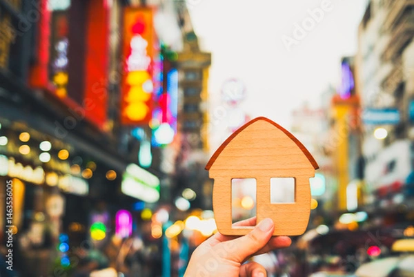 Fototapeta Businessman holding a model house in a shopping area to find a storefront for his business. The idea of ​​whether finding a storefront is still necessary in this era of growing online commerce.