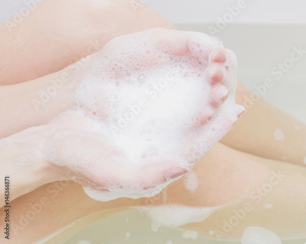 Fototapeta Beautiful female hands and legs in white soap. Cropped image.