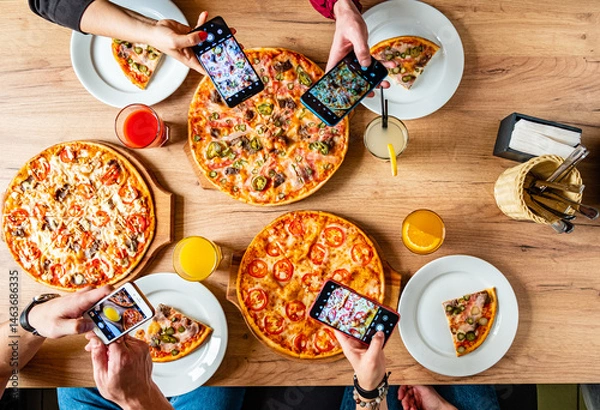 Obraz Friends savor tasty pizzas and capture memories at a vibrant gathering over shared joy