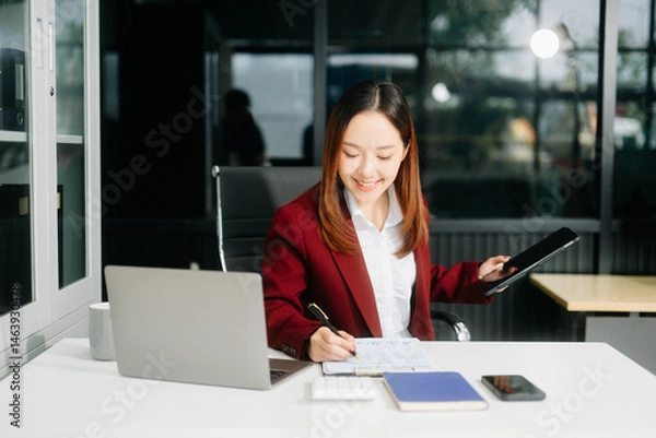 Obraz Asian business woman typing laptop and tablet Placed at the table